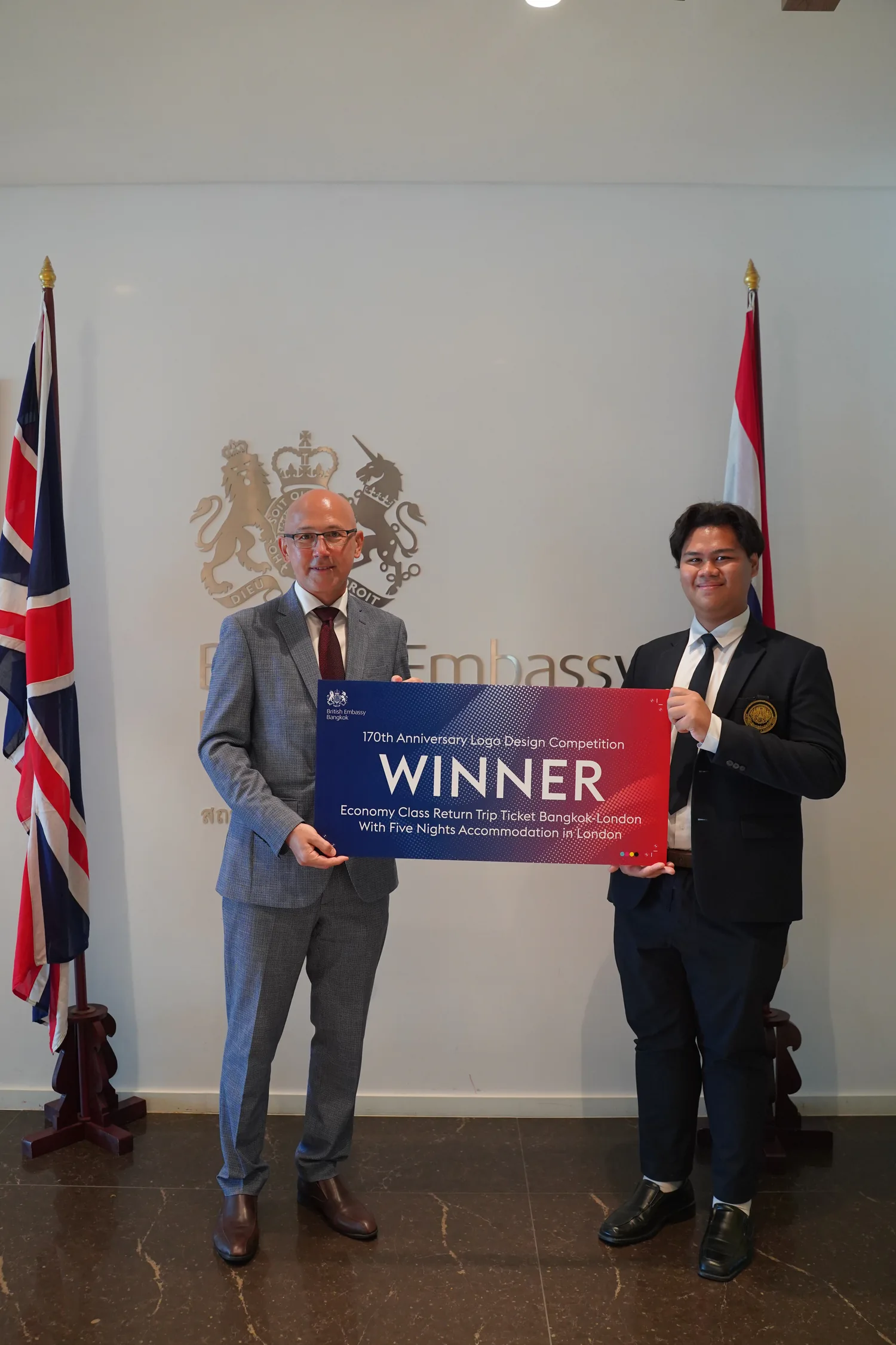 Nawanthorn Boonprasert holding the winner sign at the diplomatic relations logo award event